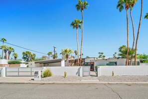 Un bâtiment moderne à l’extérieur blanc, doté d’un garage et d’une porte rouge.