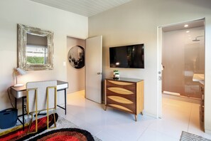Une chambre moderne équipée d’un bureau, d’une chaise, d’une télévision et d’un espace douche.