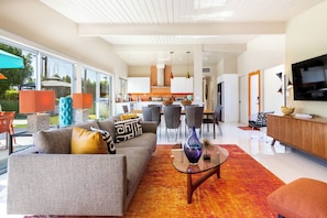 A modern living room with a sofa, coffee table, and a TV. - Modern Sunset: MCM color-filled classic (Palm Springs)
