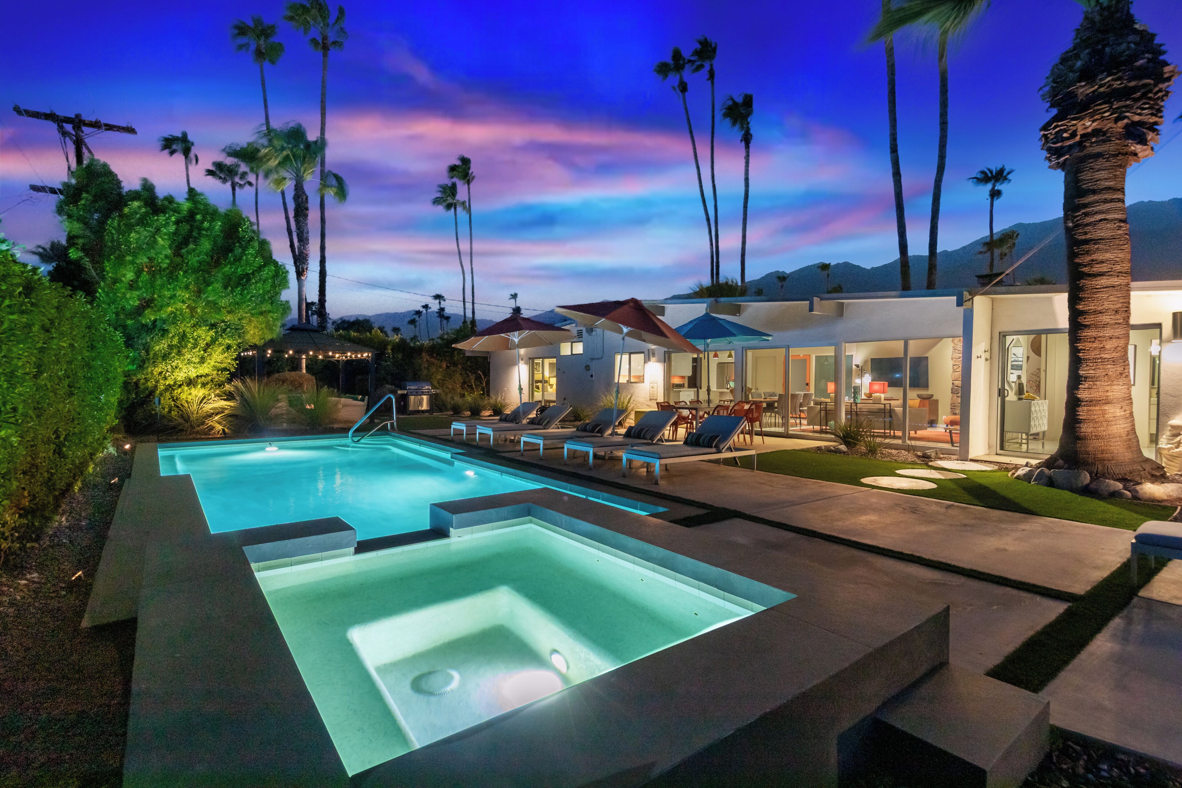 Un área de piscina moderna con jacuzzi, sillones de descanso y un espacio exterior bien iluminado.