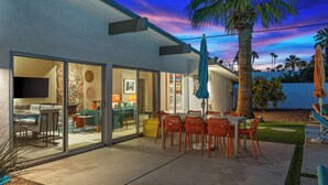 A modern house with a patio, dining area, and a TV in the living room. - Modern Sunset: MCM color-filled classic (Palm Springs)