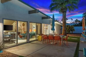 A modern house with a patio, dining area, and a TV in the living room.