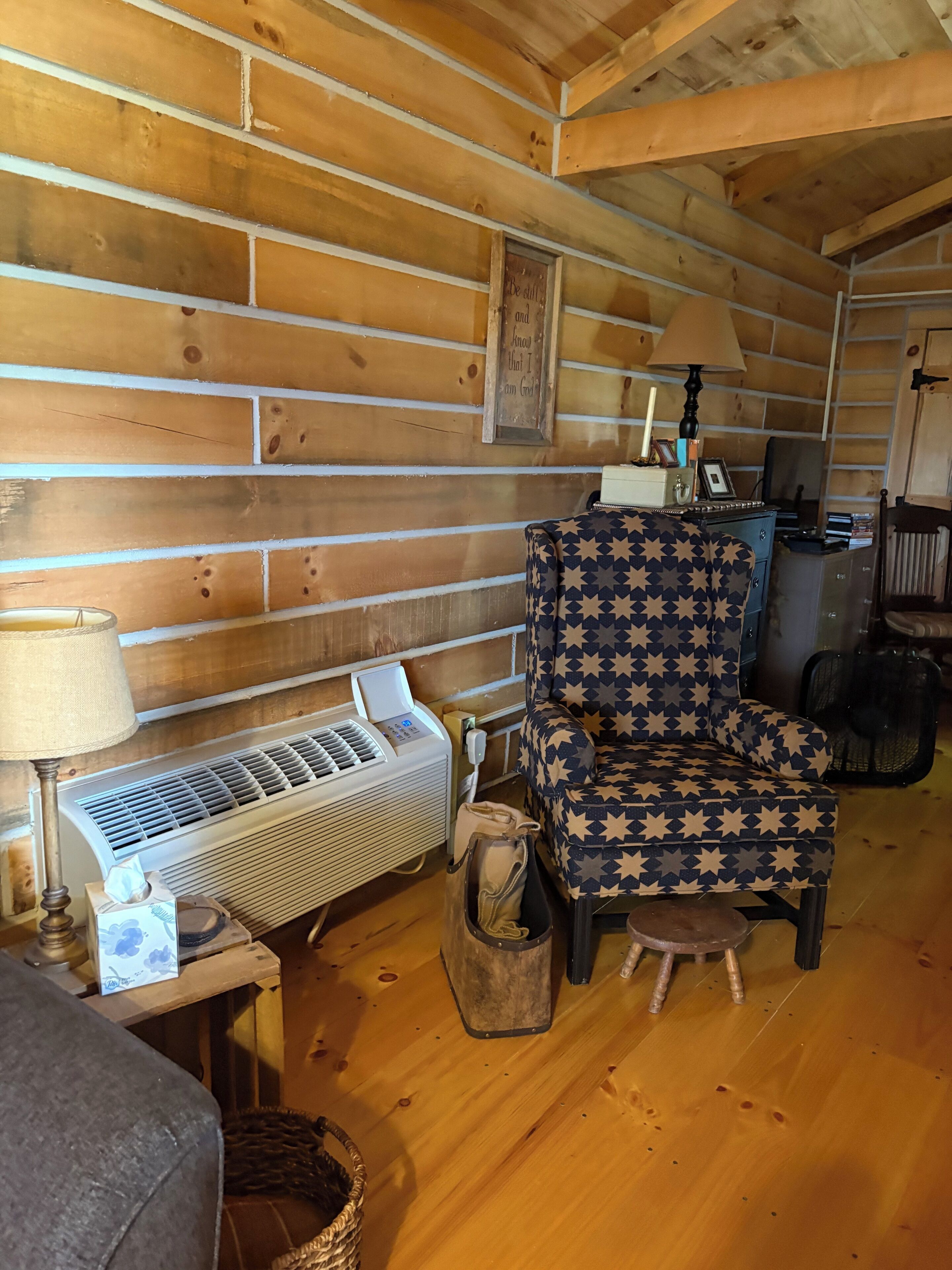 A cozy cabin interior with a star-patterned chair, a heater, and a framed inspirational quote on the wall.