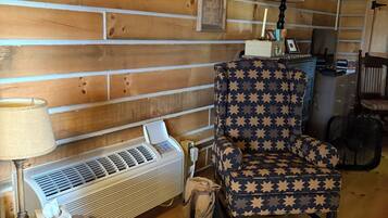 A cozy cabin interior with a star-patterned chair, a heater, and a framed inspirational quote on the wall.