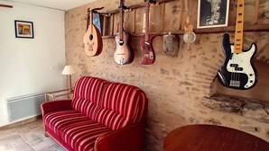 Una habitación con un sofá rojo a rayas, una silla de madera y una pared decorada con varios instrumentos musicales.