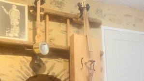 Una chimenea de piedra con un pequeño modelo de velero, un estante de madera con un objeto colgante, y una puerta blanca.