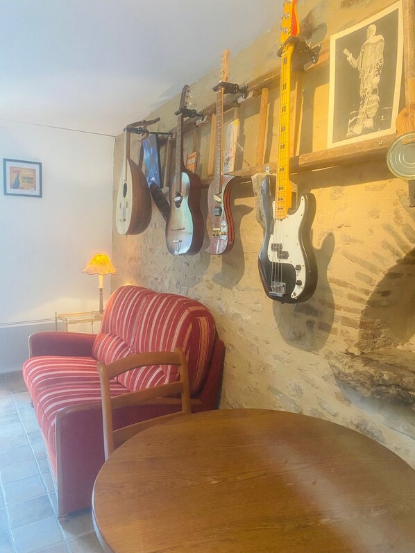 Et værelse med en rød stribet sofa, et træspisebord og flere guitarer hængende på væggen.