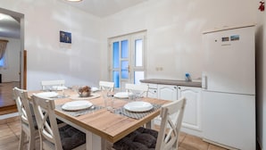 A dining area with a wooden table set for four, white chairs, and a white refrigerator.