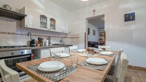 A well-lit, modern kitchen with white cabinets, a gas stove, and a dining area set for four with a wooden table.