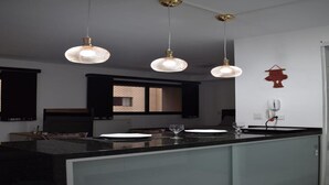 A modern kitchen with a large island, pendant lighting, and a red decorative item on the wall. - Studio near Botanical Garden (Cristo Rei Curitiba)