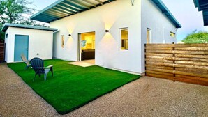 A modern house with a covered patio, a small lawn, and a wooden fence. - Modern Accessible Studio Home w/ Yard  SolMod#3 (Tucson)