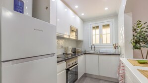 Une cuisine moderne avec des meubles blancs, un four encastré, un four à micro-ondes et un évier.
