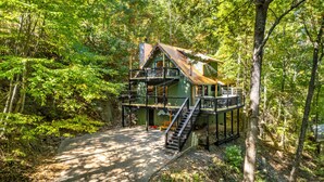 Eine rustikale Holzhütte mit einer Holzterrasse und einer Treppe zu einem Balkon im zweiten Stock.