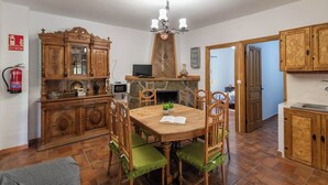 Un comedor con mesa y sillas de madera, una chimenea y una zona de cocina con armarios de madera.