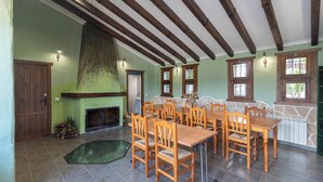 A dining area with wooden tables and chairs, a fireplace, and stone walls.