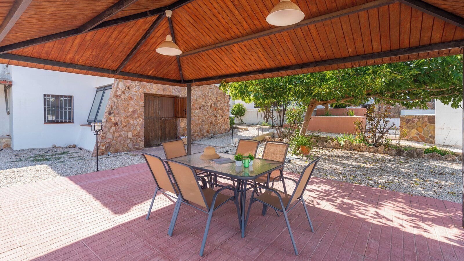 An outdoor patio with a table and chairs, a stone wall, and a wooden pergola.