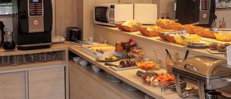 Disposición de bufé con diferentes alimentos, una máquina de café y un microondas.