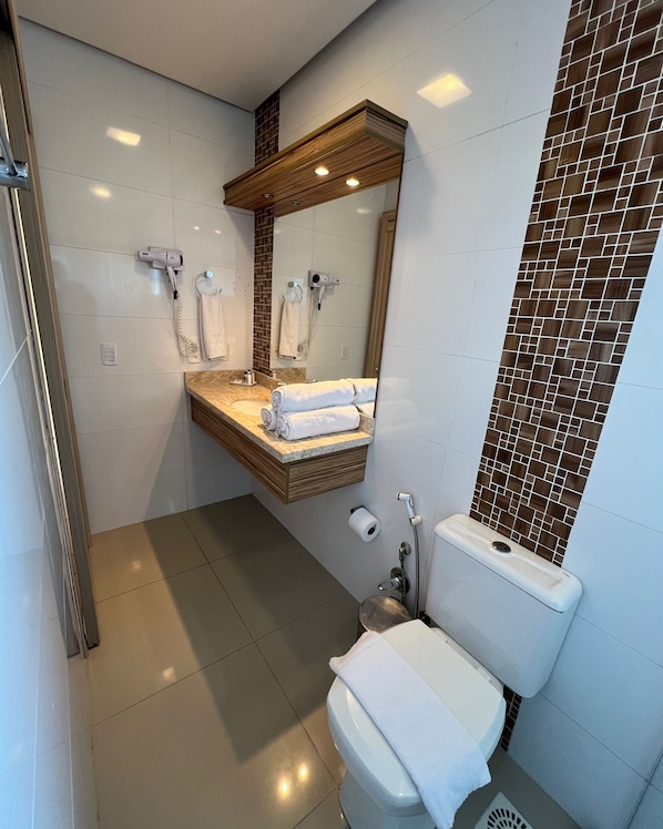 A modern bathroom with a vanity, a toilet, and a shower area. - Pousada Naala Gramado (Gramado)