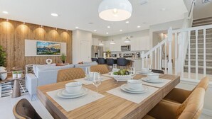 A modern dining area with a wooden table set for four, surrounded by cushioned chairs. - Spacious 5-bedroom Town home Pvt Pool, BBQ & Free Water Park Access Near Disney (Kissimmee)