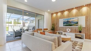 A modern living room with a sofa, chairs, a coffee table, and a TV. - Spacious 5-bedroom Town home Pvt Pool, BBQ & Free Water Park Access Near Disney (Kissimmee)