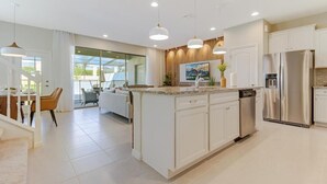 A modern kitchen with white cabinetry, stainless steel appliances, and pendant lighting. - Spacious 5-bedroom Town home Pvt Pool, BBQ & Free Water Park Access Near Disney (Kissimmee)