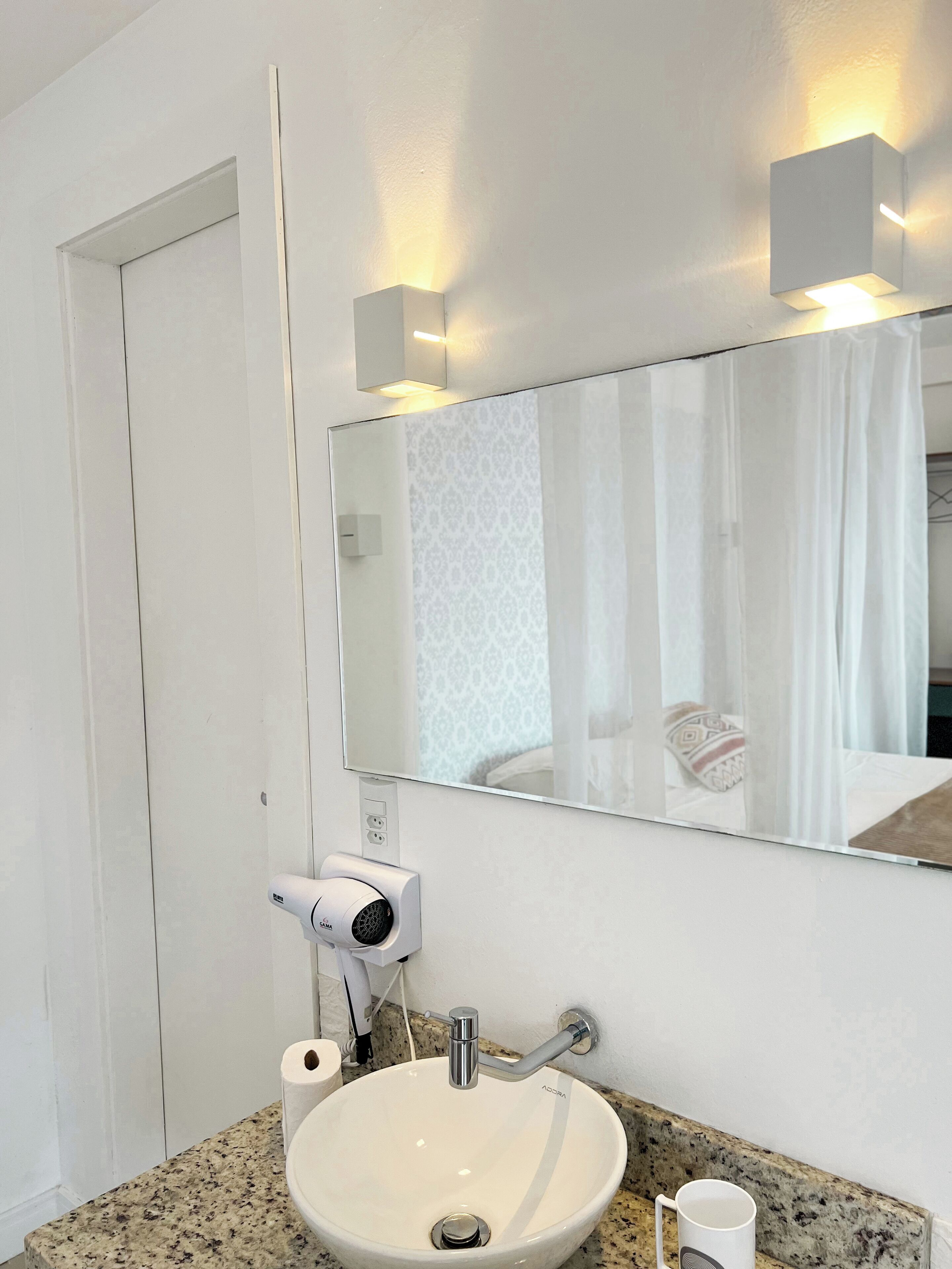A bathroom with a white sink, a mirror, and a security camera.
