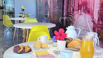 Un comedor con una mesa redonda dispuesta para el desayuno, con pasteles, una taza de café y una jarra de jugo.