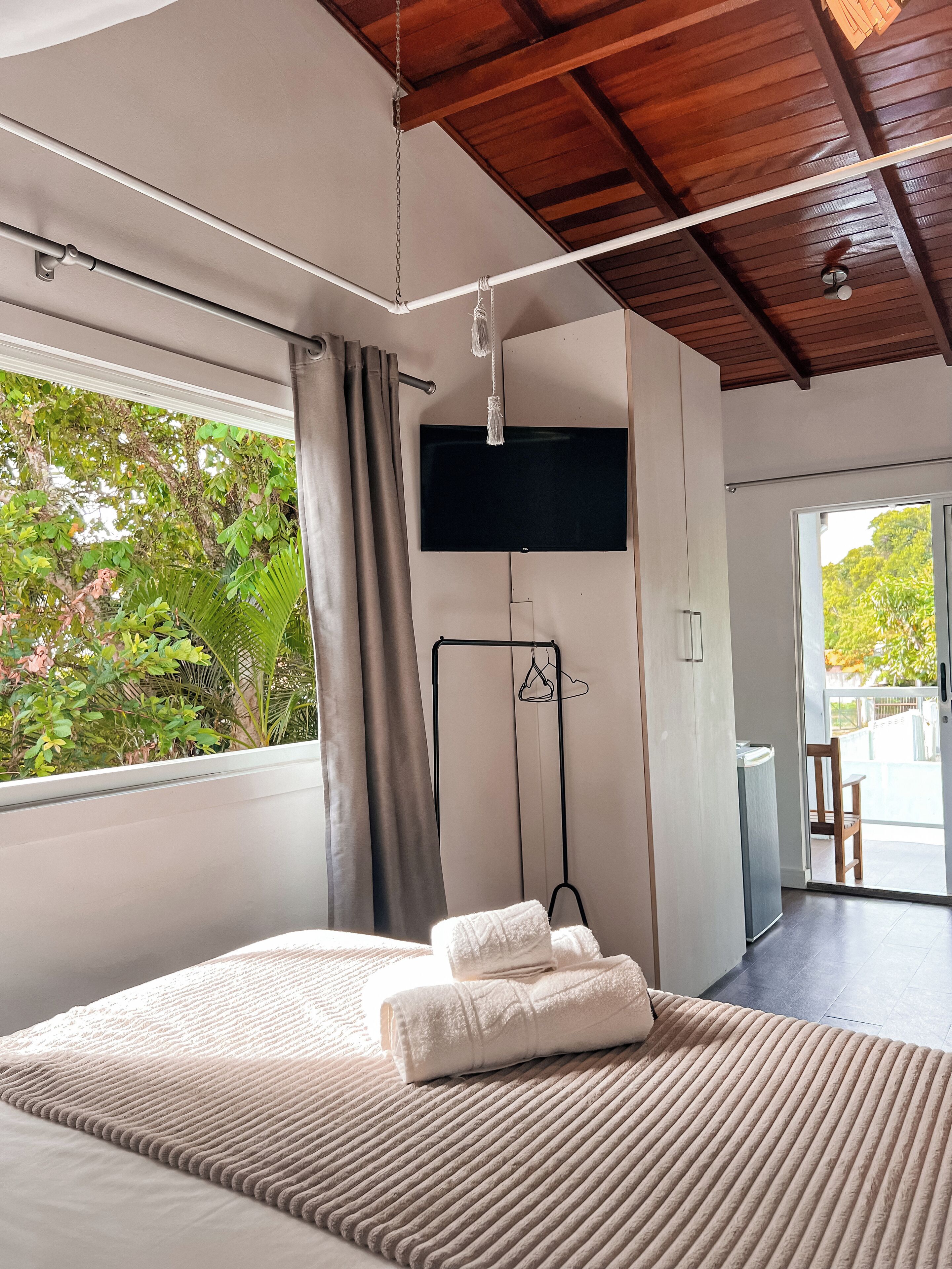 Un dormitorio moderno con una cama grande, un televisor de pantalla plana en la pared y vistas a zonas verdes.