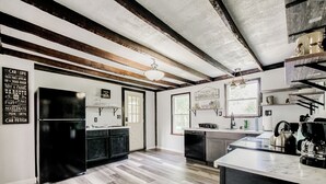 A modern kitchen with a central island, black appliances, and wooden beams on the ceiling. - Crooked Little Farmhouse! Spacious 2-bed on 2+ acres - Romeo, MI (Bruce Township)
