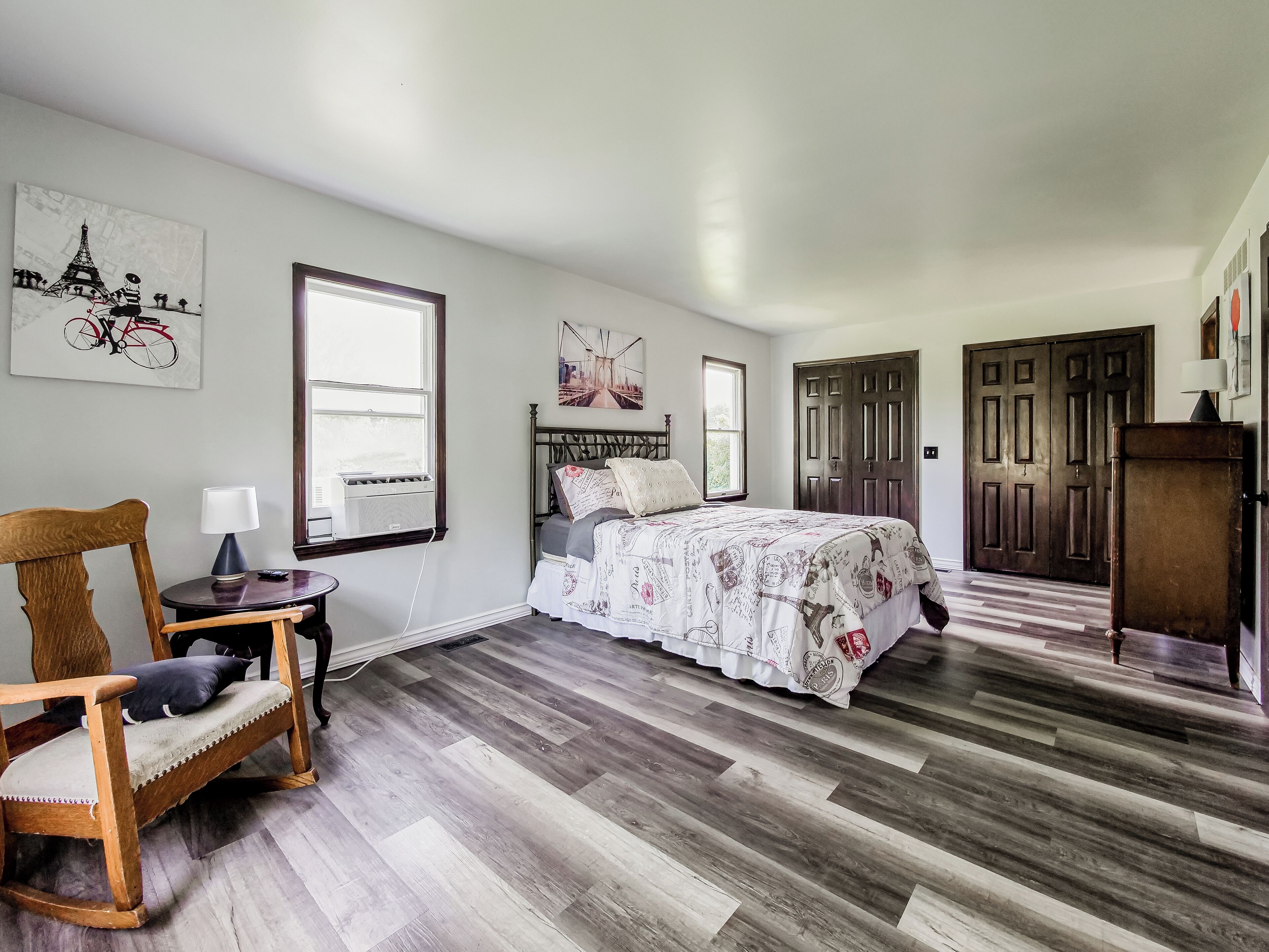 A bedroom with a bed, a chair, a window, and a door.