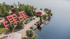 A lakeside hotel with a red building, a parking lot, and a dock with boats. - Calabogie Lodge (Calabogie)