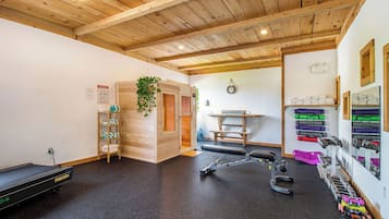Un gimnasio con vigas de madera, equipo de ejercicio y una sauna.