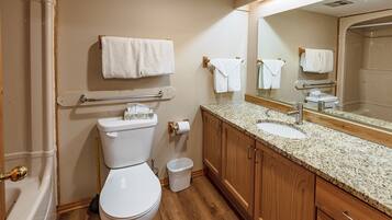 A bathroom with a toilet, sink, mirror, and wooden cabinets.