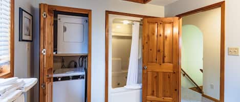 A compact bathroom with a shower, a built-in washing machine, and a small sink.