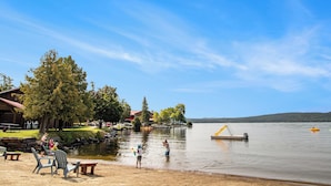 A lakeside setting with picnic tables, a dock, and a small boat. - Calabogie Lodge (Calabogie)