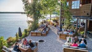 An outdoor seating area with wooden furniture and a fire pit, overlooking a body of water. - Calabogie Lodge (Calabogie)