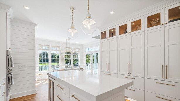 A spacious kitchen with white cabinetry, a large island, and pendant lighting.