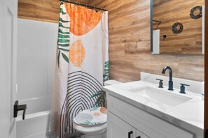 Une salle de bain avec un rideau de douche, un lavabo et un miroir.