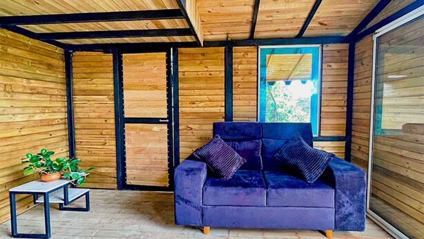 A modern interior with a wooden ceiling, a blue sofa, and a small table with a plant. - Omghat (El Peñol)