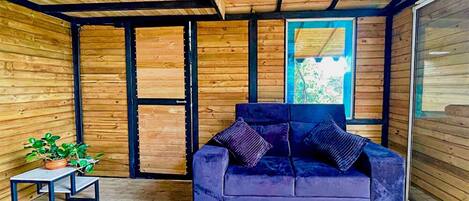 Un interior moderno con techo de madera, sofá azul y una pequeña mesa con una planta.