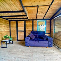 A modern interior with a wooden ceiling, a blue sofa, and a small table with a plant.