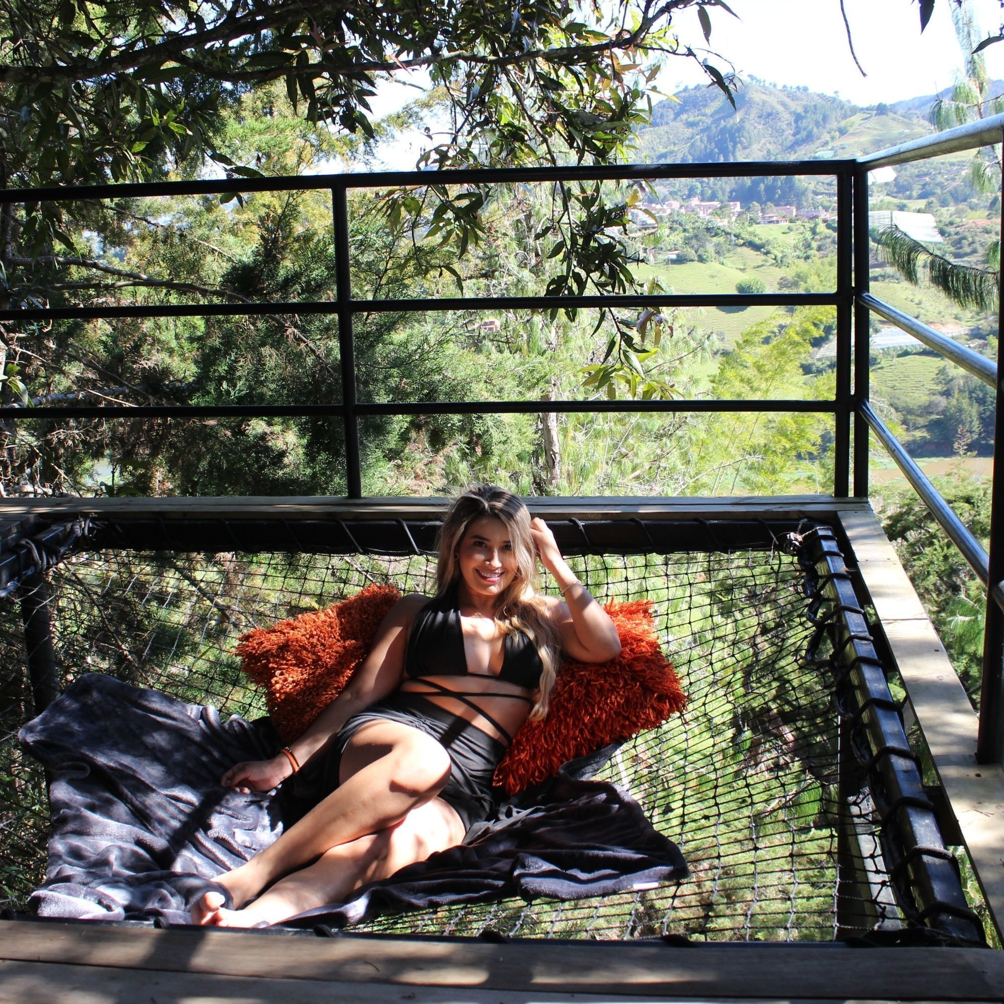 Una persona sentada en una hamaca con vista a un paisaje verde.