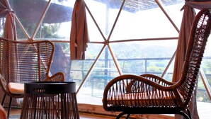 A room with a large window, wicker furniture, and a view of a mountainous landscape. - Omghat (El Peñol)