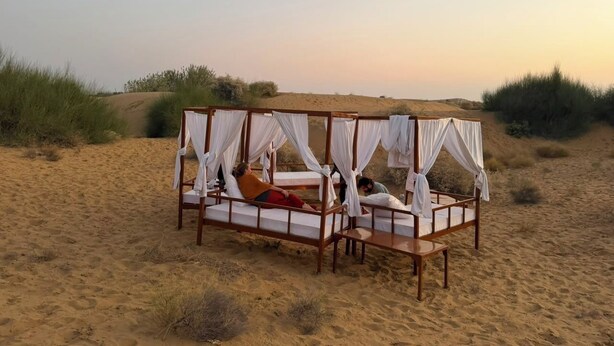 A four-poster bed with white drapes in a desert setting. - Abu Safari   (Jaisalmer)