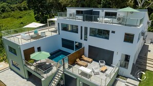 A modern two-story house with a rooftop pool, outdoor seating, and a covered patio area. - Le Gaetana hôtel (Sainte-Rose)