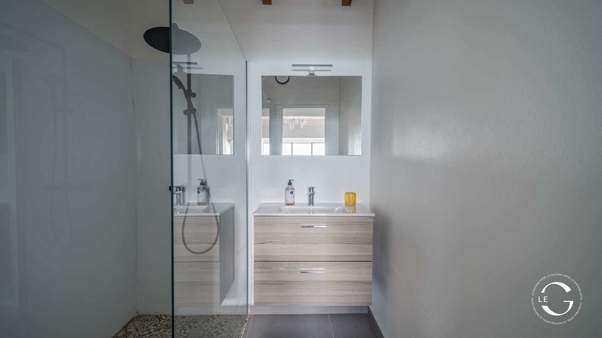 Ein modernes Badezimmer mit Duschkabine aus Glas, Waschtisch mit Spiegel und Waschbecken.