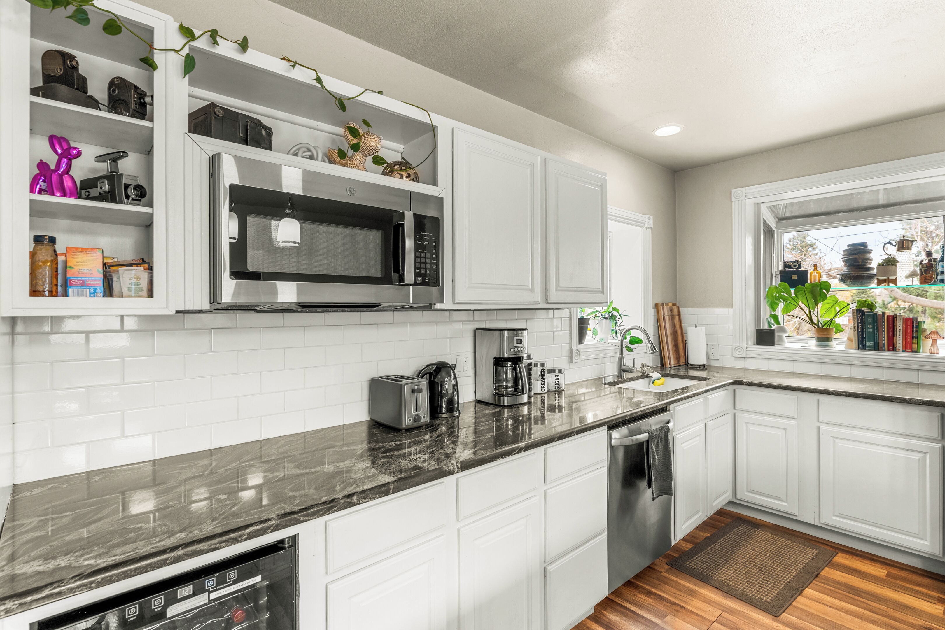 A modern kitchen with white cabinets, a stainless steel microwave, and a coffee maker.