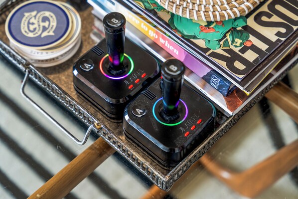 Un control de videojuegos sobre una mesa con una revista y una lata de refresco.