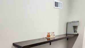 Eine Küche mit dunkler Arbeitsplatte, zwei Barhocker, einer Kaffeemaschine und einer Wandlüftung.