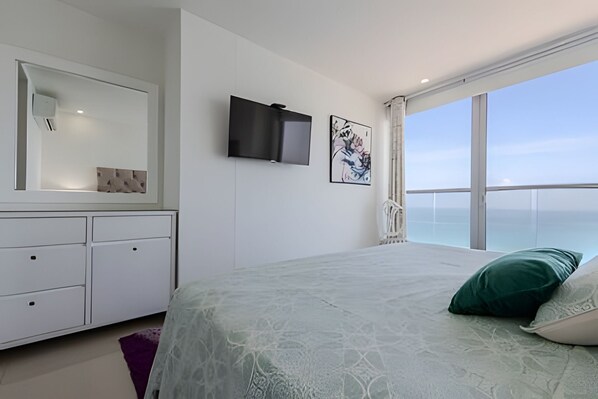 A bedroom with a large bed, a TV, a dresser, and a view of the ocean. - Luxurious Sea View & Historic Center “Morros City” (Cartagena de Indias)